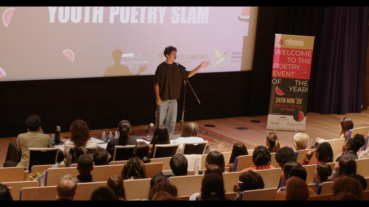Poet stands on stage speaking to audience